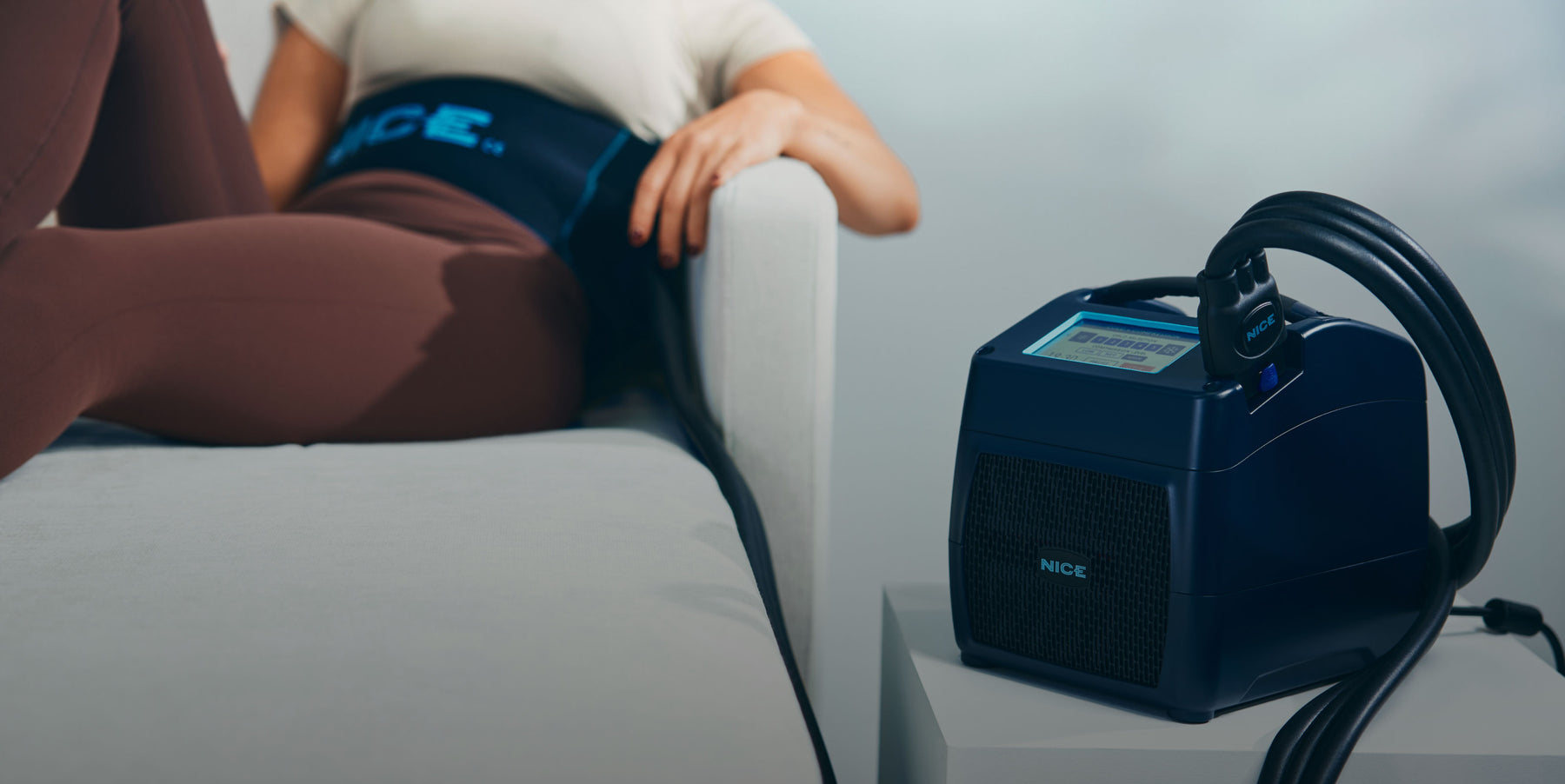 Woman using a NICE1 lumbar wrap at home during a cold and compression session